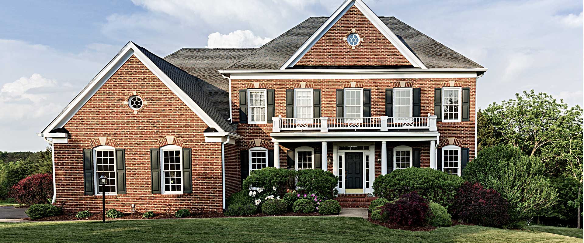 Large neo-colonial style home with wide balcony and landscaped yard